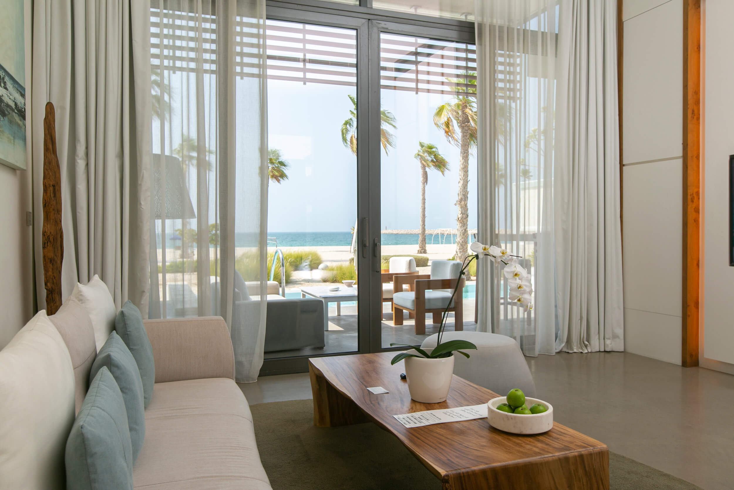 A living room sofa and coffee table looking out to the private pool and outdoor seating area